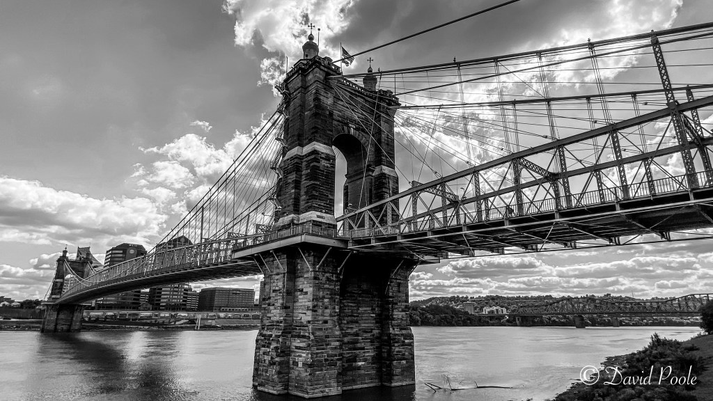 Black and white photo of the John A. Roebling Suspension Bridge in Cincinnati, Ohio, showcasing its historic structure and intricate cables