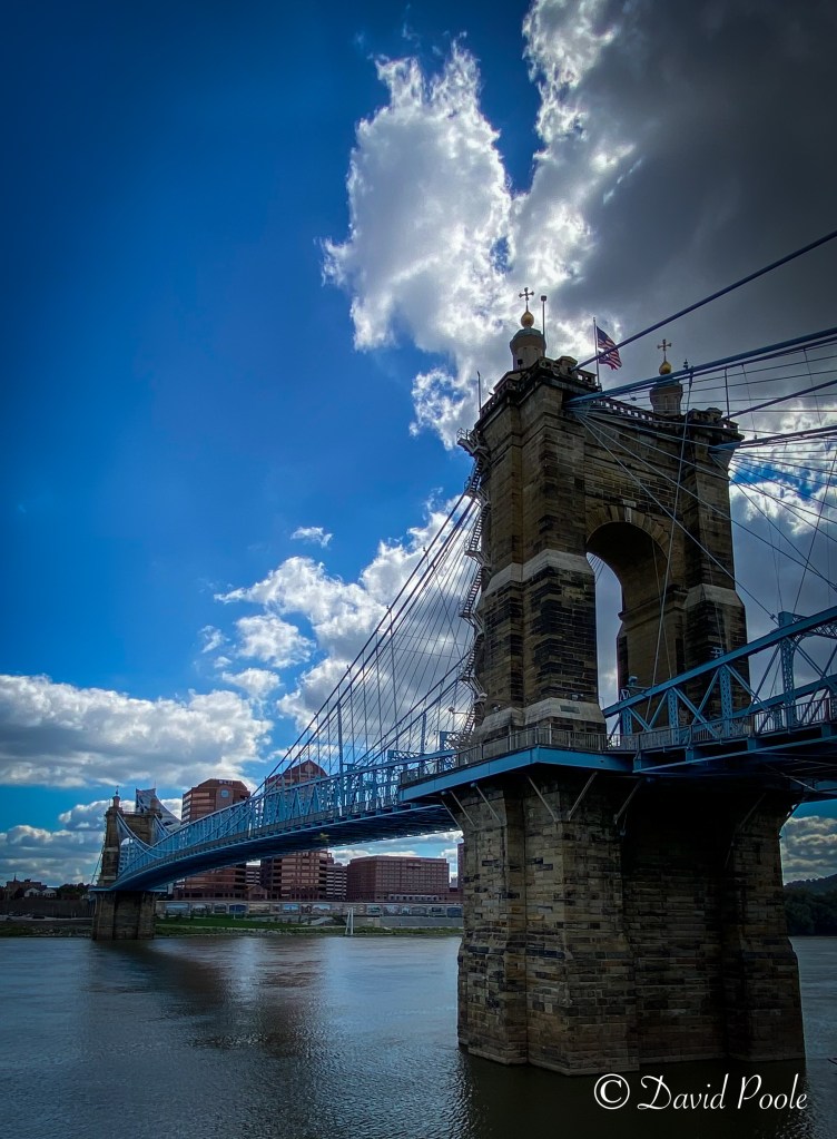 Color image of the John A. Roebling Suspension Bridge in Cincinnati, Ohio, with blue steelwork and stone towers spanning the Ohio River