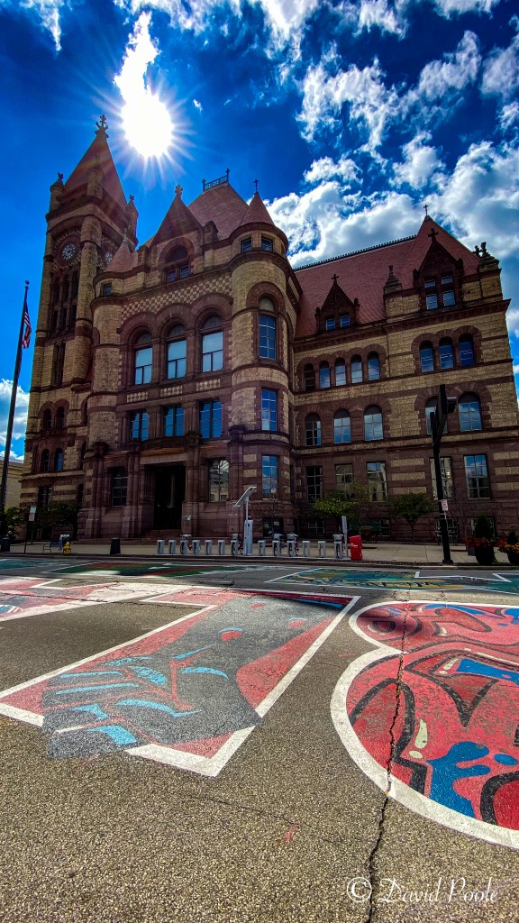 Color photograph of Cincinnati City Hall with pedestrians walking along the sidewalk, capturing urban life, architecture, and street-level details