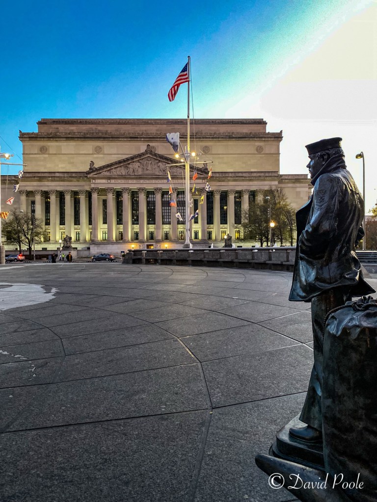 Back view of the Lone Sailor statue gazing toward the National Archives building in Washington, D.C.